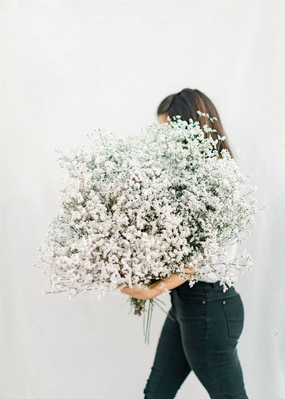 Mulher a carregar um grande ramo de flores brancas