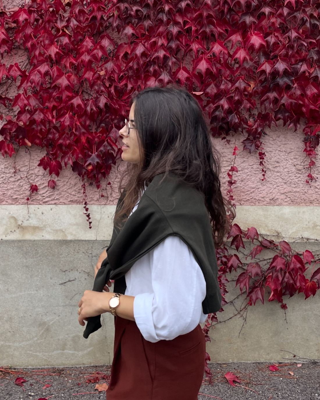 Daniela, de perfil, junto a uma parede com hera vermelha